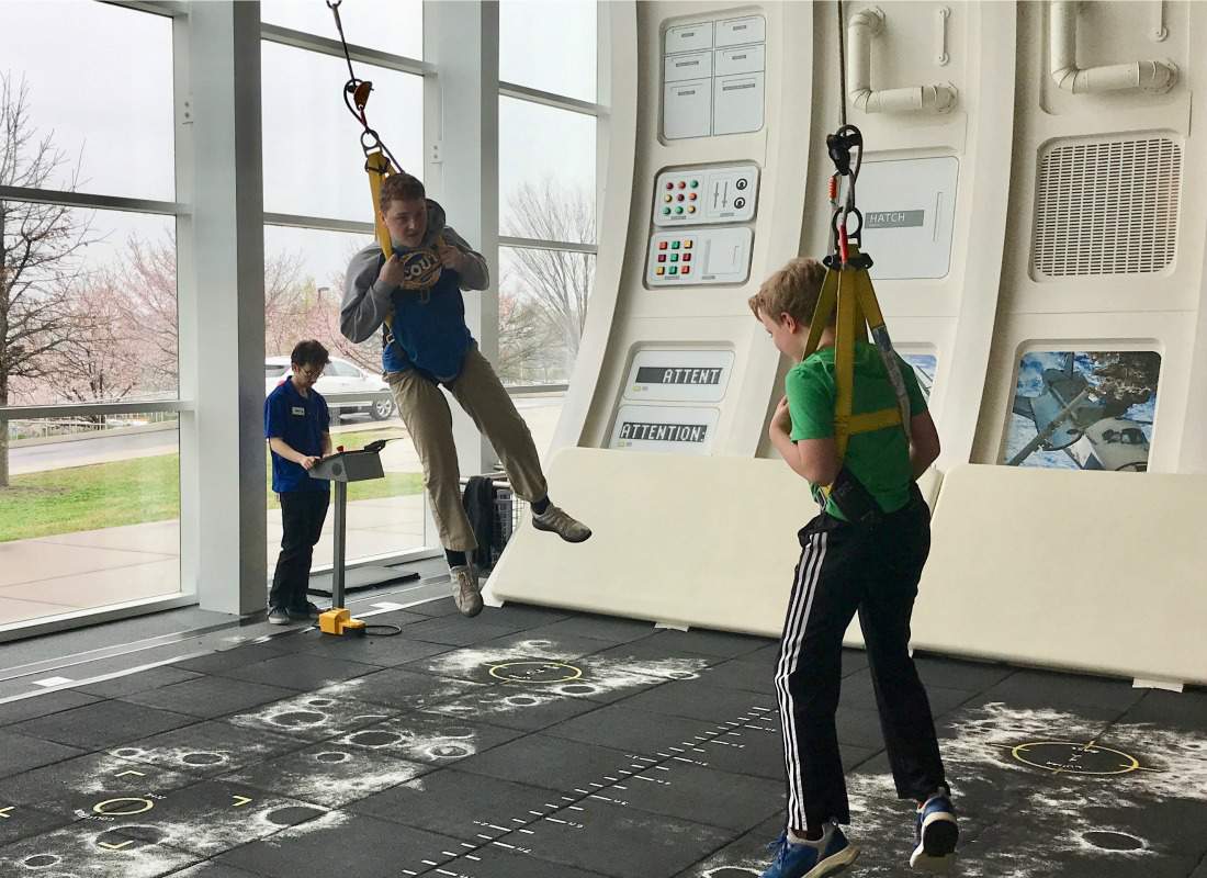 Two boys hanging in harnessnes at Adventure Science Center.