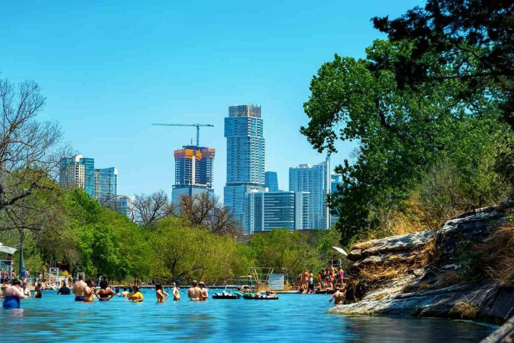 View of a natural pool in Austin, Texas with people swimming in it and trees around it.