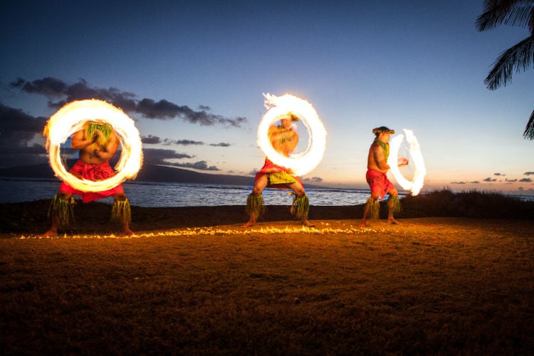 Dances with rings of fire on a beach.