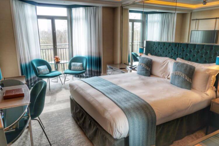 Bed and sitting area of hotel room with styllish turquoise accents.