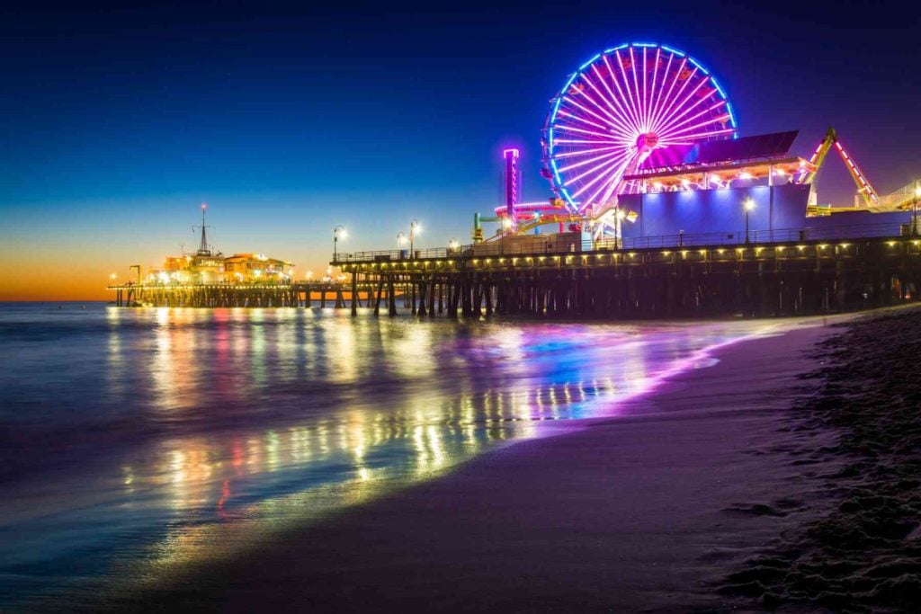 Image of the Santa Monica Pier with a lit up Ferris wheel at night.