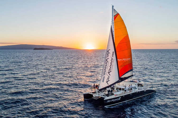 Catamaran sailing at sunset.