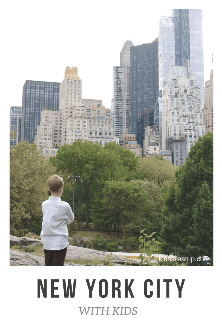 Boy in Central Park looking up at NYC buildings.